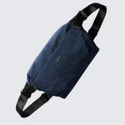 A navy blue Bellroy Venture Sling 9L with a black shoulder strap, main compartment, and a front zip pocket, designed for all-day adventure and organization.
