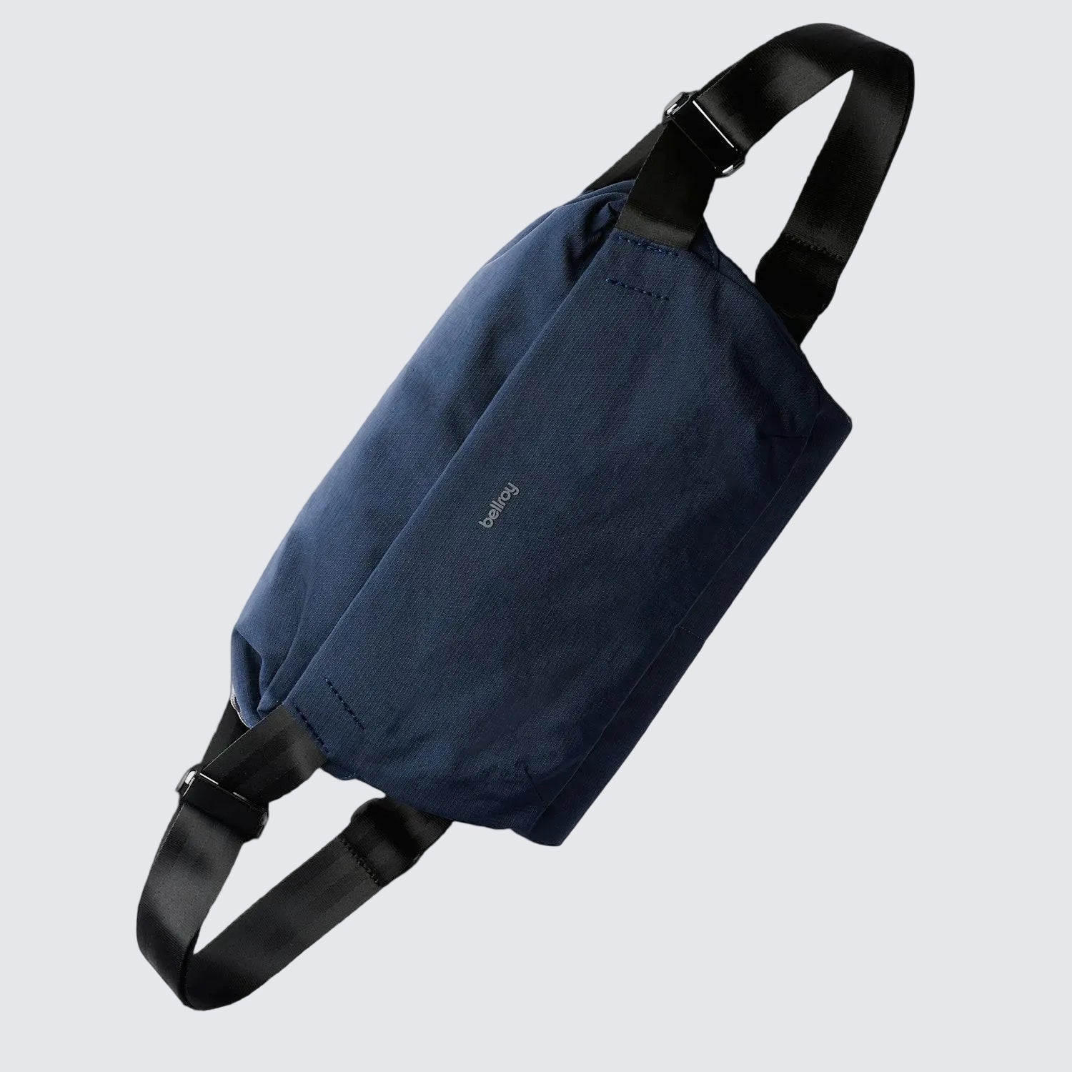 A navy blue Bellroy Venture Sling 9L with a black shoulder strap, main compartment, and a front zip pocket, designed for all-day adventure and organization.