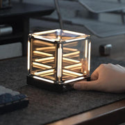 Cube-shaped LED ambient desk lamp with a hand holding it, showcasing modern minimalist lighting design.