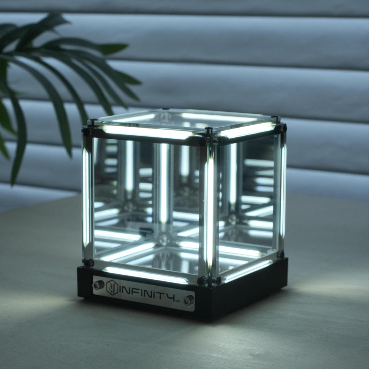 Glass cube with INFINITY branding displayed on a light surface, highlighting modern aesthetic design piece.