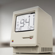 Hand holding the Retro Macintosh Clock digital alarm clock with a digital display showing time, date, and temperature